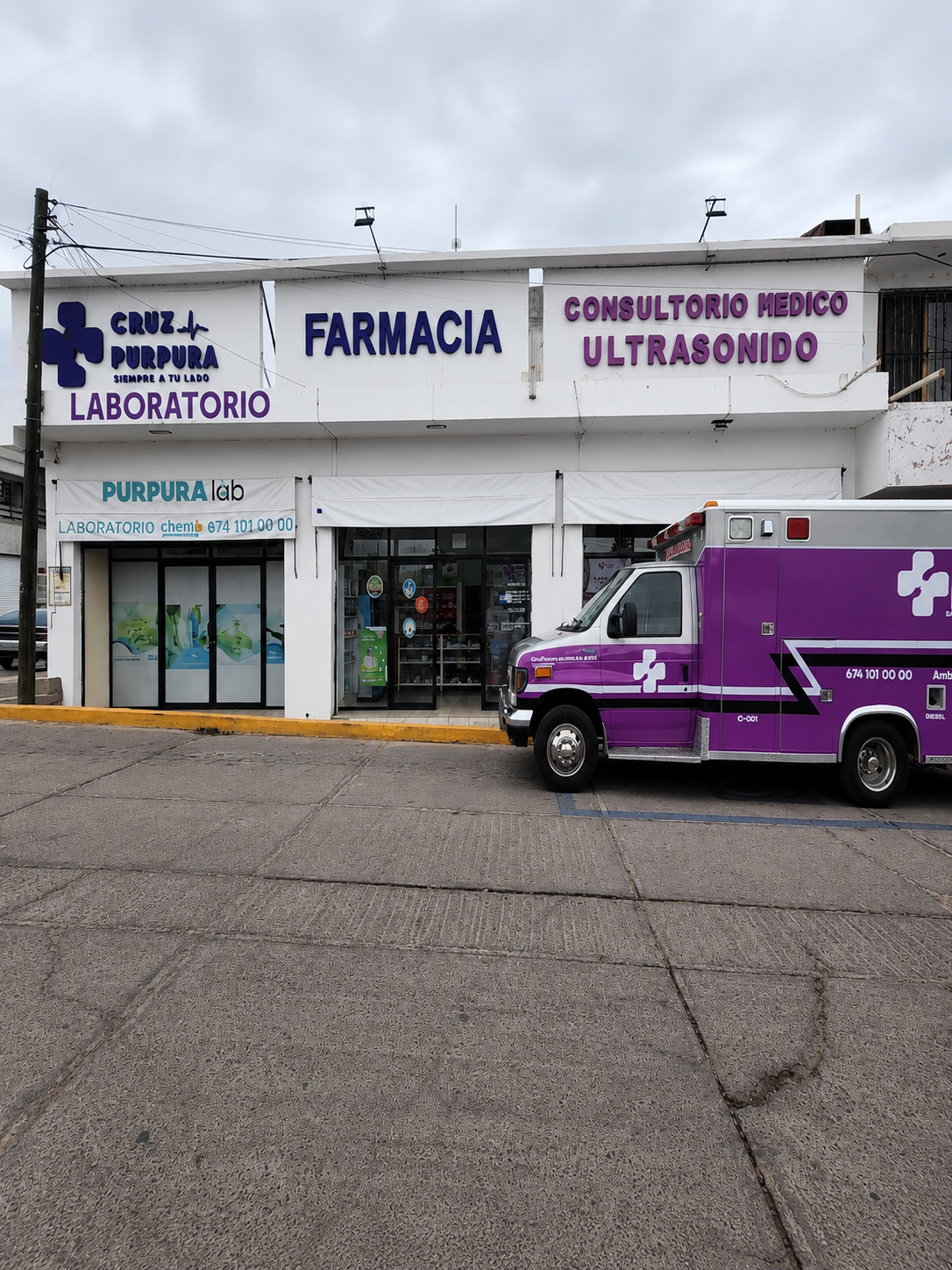 Fachada de Farmacia Cruz Púrpura con letreros morados, número 674 688 0929 y servicios de ultrasonido.