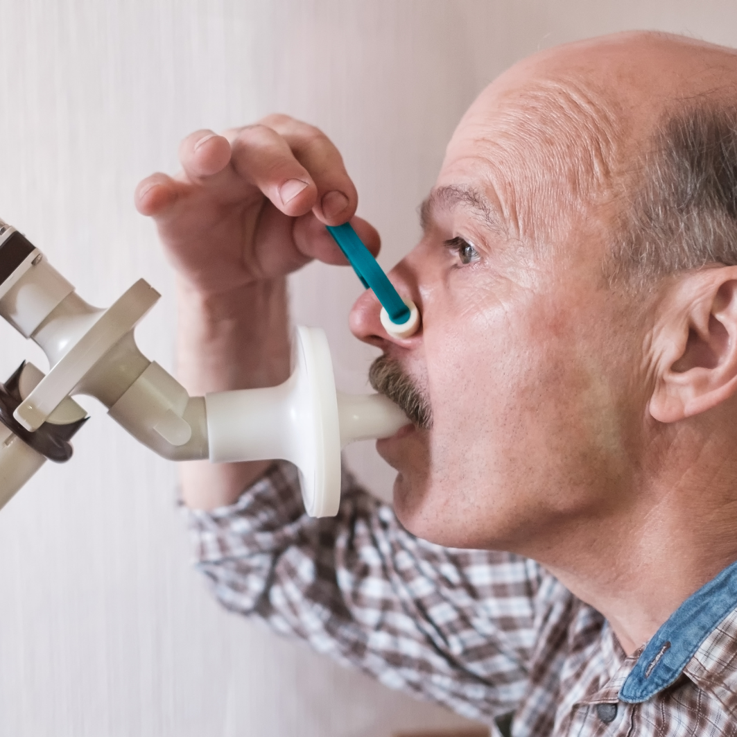 Paciente realizando una prueba de espirometría utilizando un dispositivo médico para medir su capacidad pulmonar.