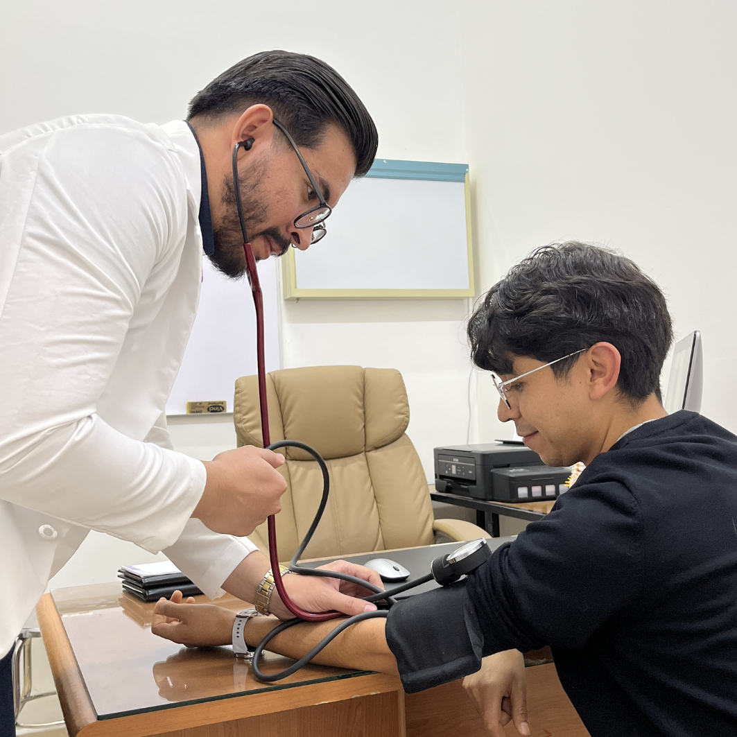 El Dr. Eduardo Guerrero Almodóvar realizando una toma de presión arterial a un paciente en el consultorio.