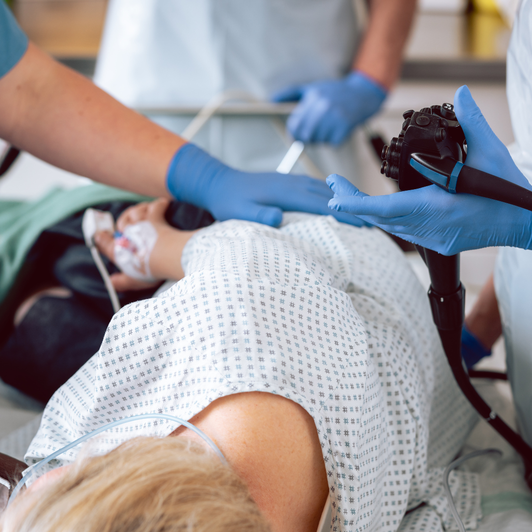 Personal médico con guantes azules preparando un endoscopio para realizar un estudio gastrointestinal a un paciente