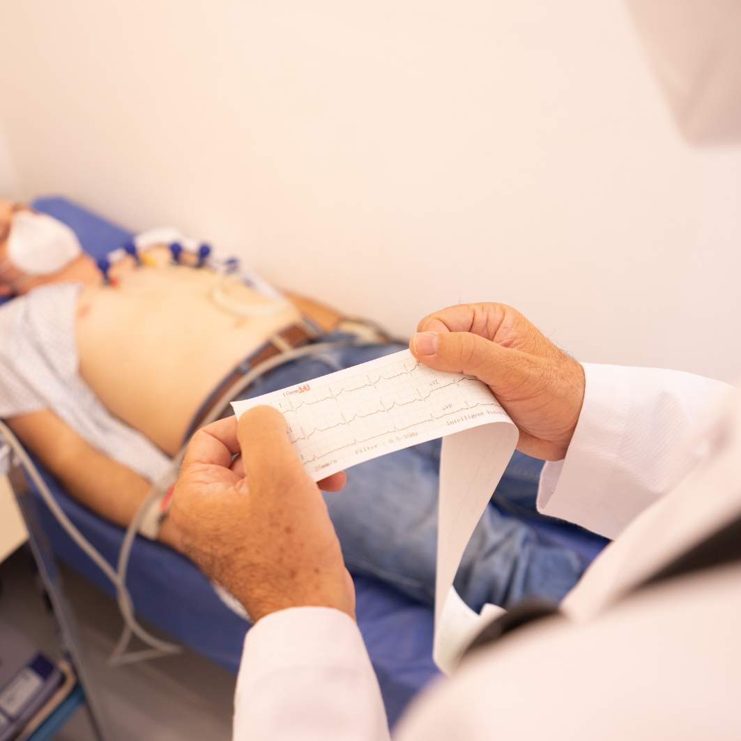 Médico analizando los resultados de un electrocardiograma (EKG) impresos en papel térmico.