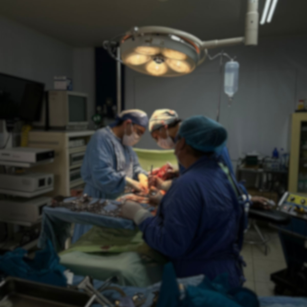 Equipo médico realizando una cirugía bajo una lámpara de quirófano en una sala equipada